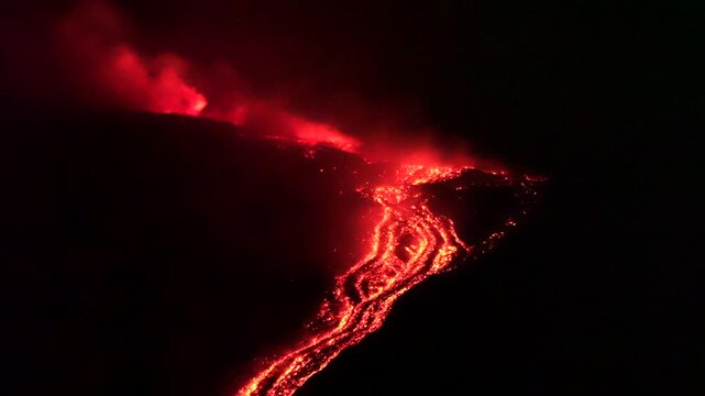 Mount Etna eruption near Catania Sicily Italy on August 7 2026 glowing lava streams down the volcanic slope at night as fiery vents illuminate thick smoke above the active volcano at night