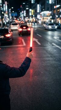 Traffic officer directing vehicles at night with glowing red stop wand, illuminated city street with bokeh effect