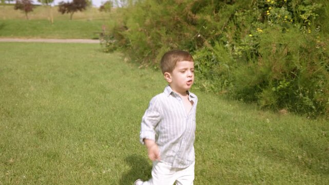 Little boy running happily through green grass