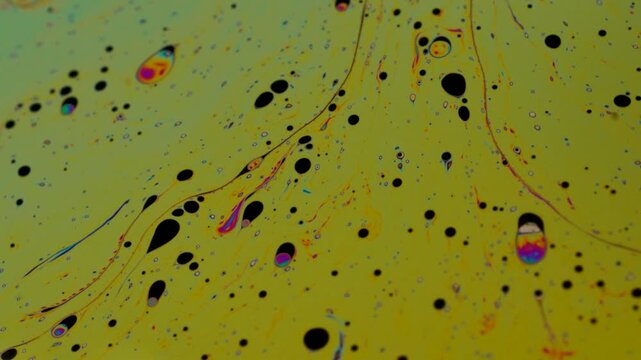 Abstract Macro Liquid Flow with Floating Black Oil Droplets and Iridescent Swirls on Yellow Gradient