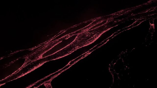 Mount Etna volcano in Sicily Italy covered by glowing lava streams flowing down the dark slopes at night creating branching patterns of molten rock during an active eruption