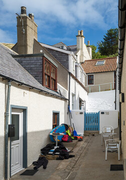 Surfboarder gear rests in a narrow coastal alleyway on a sunny day in the village of Gardenstown located in the Aberdeenshire region of Scotland