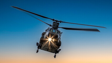 Heavy lift military helicopter flying at sunrise. Powerful headlight has starburst beams. © Robert Parker