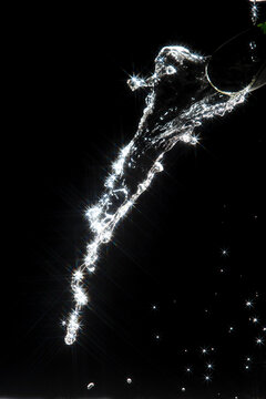 Water splash reflect bright light, producing starburst effect and shining flare, almost like falling star. Splash water under light show sparkle light flare, created bright abstract reflection
