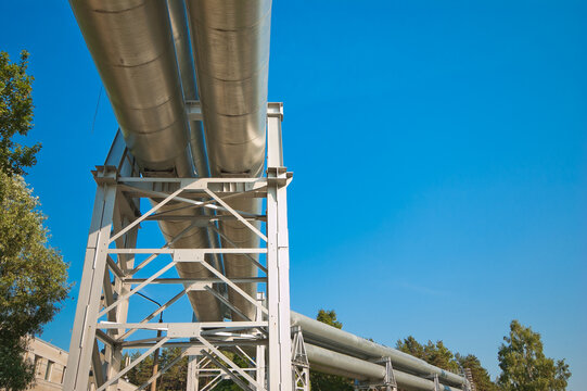 The photo shows a pipeline on a metal support against a blue sky, viewed from below