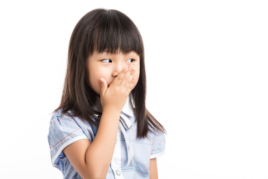 Little girl covering her mouth with hands, feeling shocked or keep a secret.