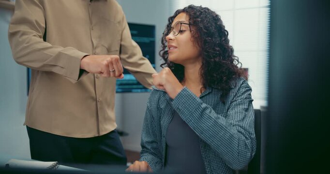 Diverse team programmers give fist bump to celebrate success at desk in office. Professional developer teamwork collaboration, Secure computer network system, Advanced cybersecurity AI data concept.