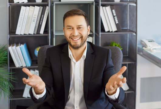 Businessman in office making gesture during video call. Employee smiles and gestures as skilled presenter, sharing webinar tips and remote communication online during conference. Technology concept.