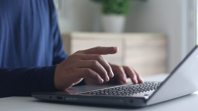Man using his finger to type on laptop for shopping online at table. Male hands typing on laptop at desk, close-up view. Person fingers are typing text on laptop keyboard. Businessman working computer