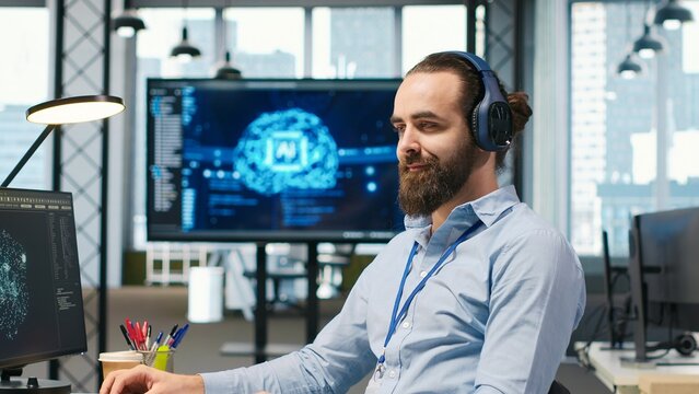 Programmer wearing headphones tests generative AI algorithms and large language model code while listening to music to improve productivity.