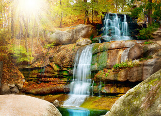 Sunlit waterfall cascading down mossy rocks in autumn forest with waterfall landscape outdoors sunlight wilderness ©  SobuzForge