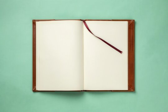 Antique open book with blank pages flat lay, vintage leather notebook with bookmark on pastel green background, top view empty diary for journaling