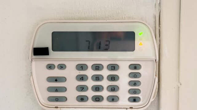 Close-up view of a modern home security alarm system keypad on a wall next to a doo. Remote protection system concept. Smart devices and technology