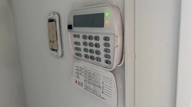 Home security alarm keypad with flashing lights indicating the system is armed for protection, ensuring safety against burglary and unauthorized entry