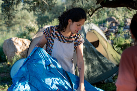 Young woman setting up tent during camping trip