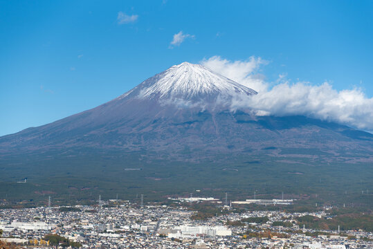 A scenic panoramic view of snow-capped Mount Fuji overlooking Fujinomiya city from Shirao Mountain Park (Shiraosan) on a sunny December afternoon. Horizontal shot.