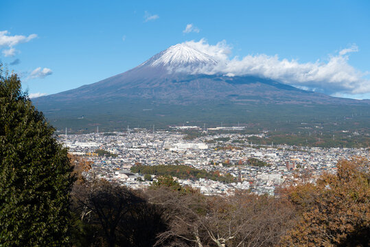 A scenic panoramic view of snow-capped Mount Fuji overlooking Fujinomiya city from Shirao Mountain Park (Shiraosan) on a sunny December afternoon. Horizontal shot.
