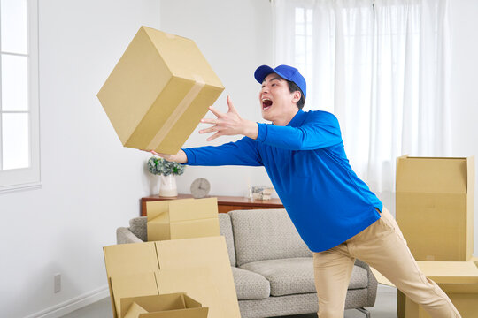 段ボールを落としそうになり慌てる引っ越し業者の男性