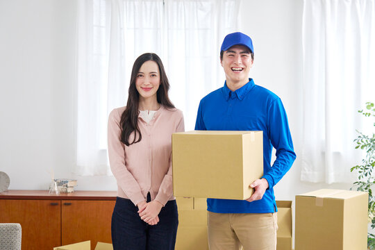 段ボールを持つ笑顔の引っ越し業者と女性