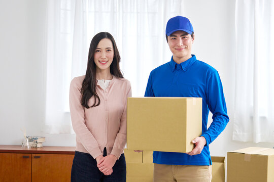 段ボールを持つ笑顔の引っ越し業者と女性