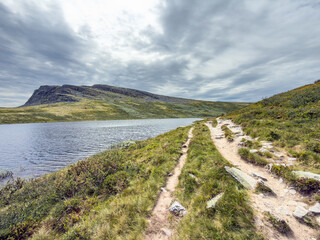 Fototapeta premium Sandy footpath beside a mountain lake in Rondane, Norway