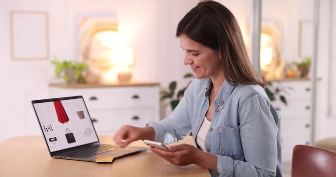 Woman with credit card using laptop and smartphone for shopping online at wooden table indoors