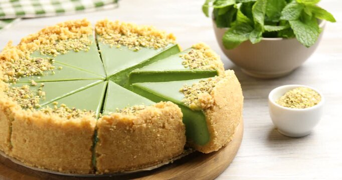 Tasty matcha cheesecake, powder and mint on wooden table, closeup. Camera moving right