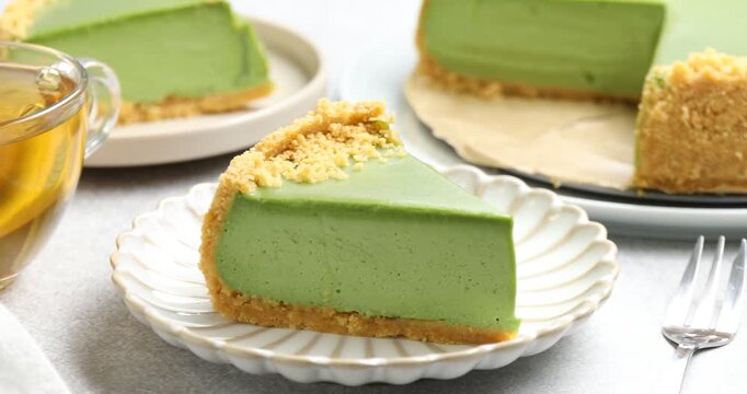 Tasty matcha cheesecake and cup of tea on light grey table, closeup. Camera moving right