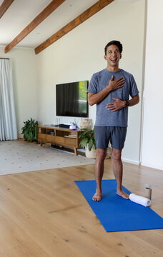 African American man practicing breathing at home on yoga mat in workout shorts, bottle, copy space