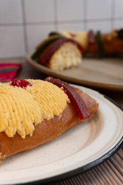 Slice detail of "Rosca de Reyes" or Epiphany bread, placed on a wooden table