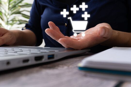 Hands present glowing shopping symbol over laptop