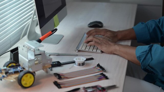 Engineer programming robot using computer in modern office
