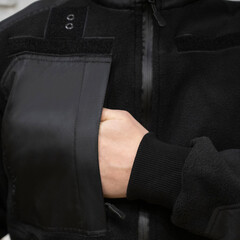 Person Reaching into Pocket of Black Fleece Jacket © Алексей Божко