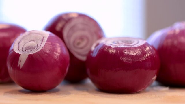 Fresh peeled red onions on a wooden cutting board close up view.