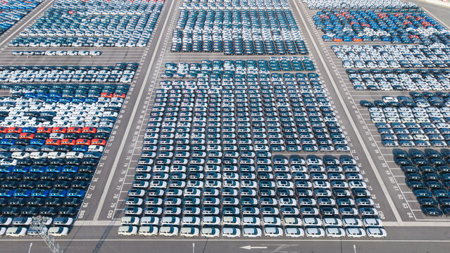 Aerial top‑down view of massive new car storage lot with neatly arranged vehicles
