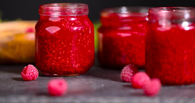   homemade jam in transparent jars, berry jam made from natural raspberries is on a dark stone slate tile