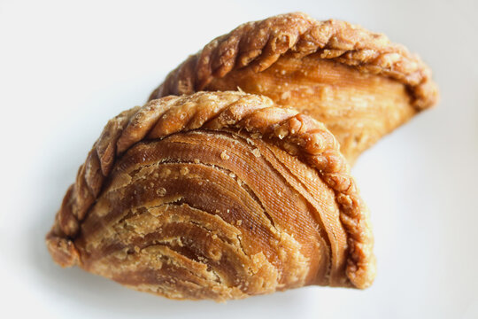 Two golden crispy spiral curry puffs with braided edges.
