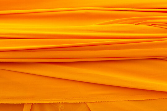 Buddhist yellow cloth draped elegantly. Traditional saffron fabric used in religious ceremonies. Vibrant textile from Thailand with rich cultural significance.