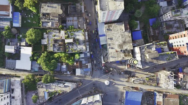 A 90-degree top-down drone view of a city showing vehicles and pedestrians moving along roads and through intersections. The slow-paced footage captures everyday traffic and movement in an urban area.