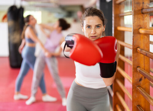 Girl in boxing gloves during training, athlete boxes, performs series of repetitions. Gym, sport as system of values, lifestyle. Girl and boxing, working with body and spirit.