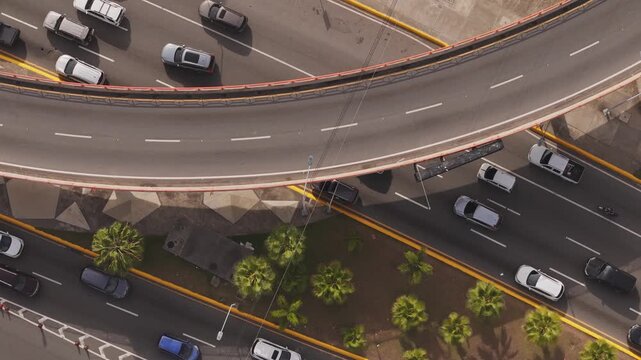 Straight down top-down drone shot of cars traveling across a curved highway overpass flyover