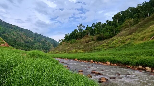 Landscape view from the riverbank of a clear stream flowing and splashing over rocks at Khun Dan Prakan Chon Dam in Nakhon Nayok, Thailand