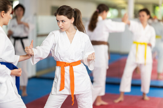 In gym, female athletes work in pairs and learn to use classic karate techniques to repel opponents blow, hone melee skills, strengthen spirit. Sport as lifestyle..