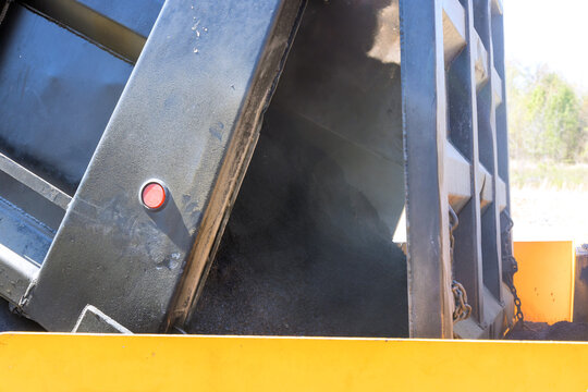 Dump truck unloading hot asphalt at construction site
