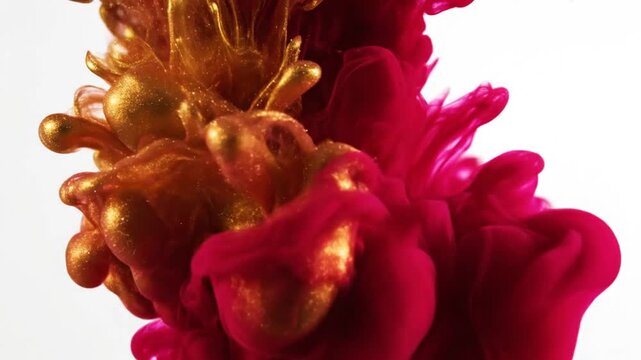 Red and gold ink swirling in water on white background