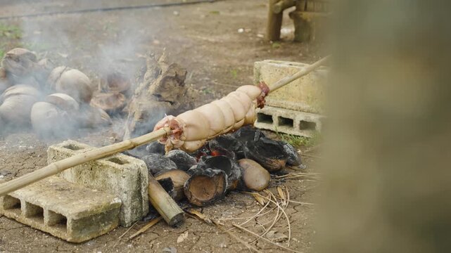 Pork Belly Slowly Rotating Over a Grill During Cooking