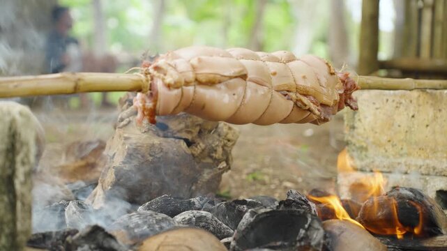 Close-Up of Pork Belly Slowly Rotating Over a Grill During Cooking