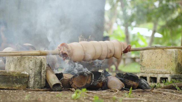 Pork Belly Slowly Rotating Over a Grill During Cooking