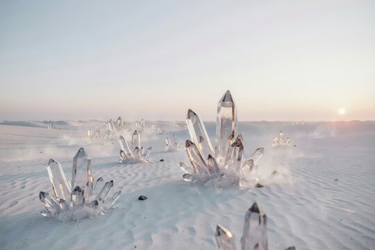 Large clear quartz crystal clusters emerging from white sand dunes in a vast desert landscape under a soft pastel sunset sky horizon
