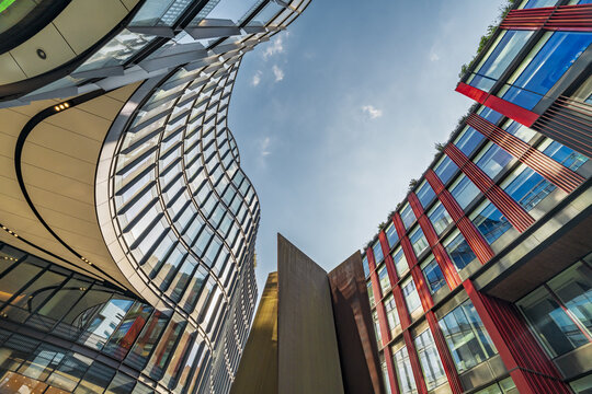 View of modern glass and steel architecture with curved facades and red structural elements in the City of London, London, England, United Kingdom.